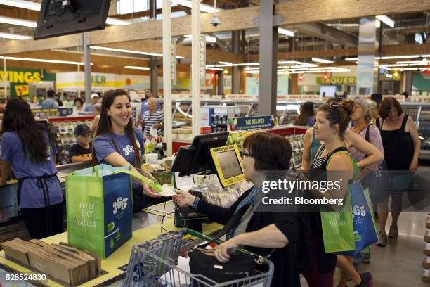 An employee hands a receipt to a customer at a cash register during the grand opening of a Whole Foods Market 365 location in Santa Monica,...