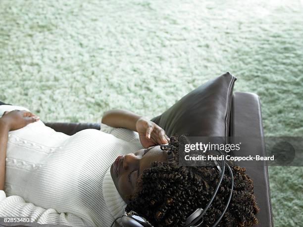 young black woman relaxing listening to headphones - heidi coppock beard stock-fotos und bilder