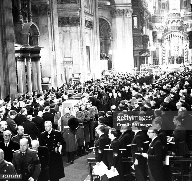 Through the mourning congregation, the flag-draped coffin of Sir Winston Churchill is borne by Grenadier Guards along the aisle of St. Paul's...