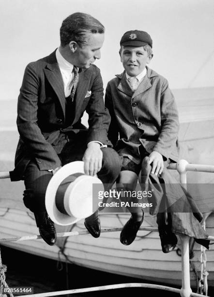 Sitting on the rail of the 'RMS Olympic', silent Charlie Chaplin chats to a young admirer as the ship prepares to dock in Southampton.