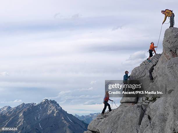 family of hikers on rock cliff, roped together - climbing a mountain stockfoto's en -beelden