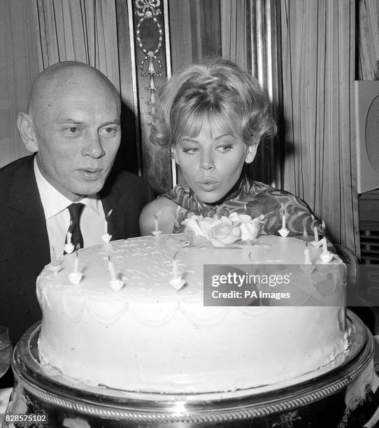 Actor Yul Brynner and Swedish-born actress Britt Ekland join forces to blow out the candles on a birthday cake at a reception at the Dorchester...