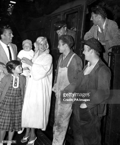 Hollywood actress Jayne Mansfield proudly holds her eight-months-old son Miklos Hargitay as she chats to railwaymen on a platform at Euston station....