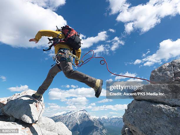 climber jumps across rock gap, makes contact - auf etwas treten stock-fotos und bilder