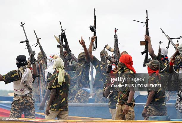 Fighters with the Movement for the Emancipation of the Niger Delta raise their riffles to celebrate news of a successful operation by their...