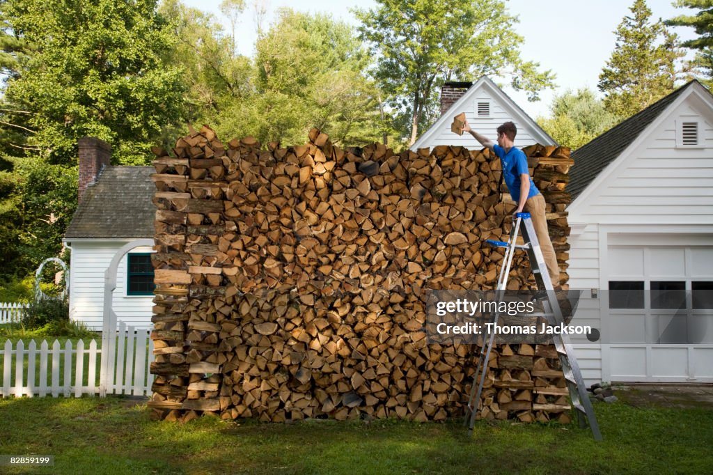 Man on ladder, stacking wood