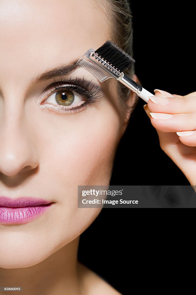 Woman combing her eyebrow