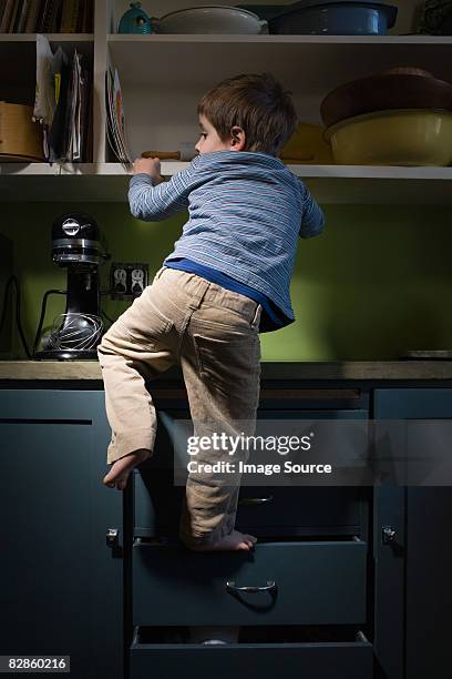 boy climbing in kitchen - low risk stock pictures, royalty-free photos & images