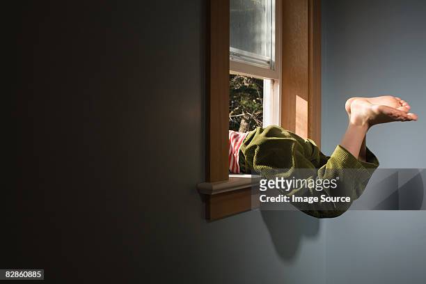 boy climbing out of window - fuggire foto e immagini stock