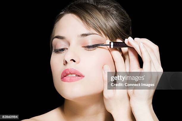 woman applying eyeliner - eye liner photos et images de collection