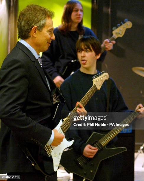 British Prime Minister Tony Blair plays the guitar with pupils during a visit with Home Secretary David Blunkett to the Firth Park Community College...