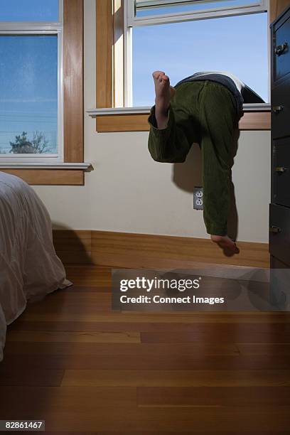 boy climbing out of window - window dresser stock pictures, royalty-free photos & images