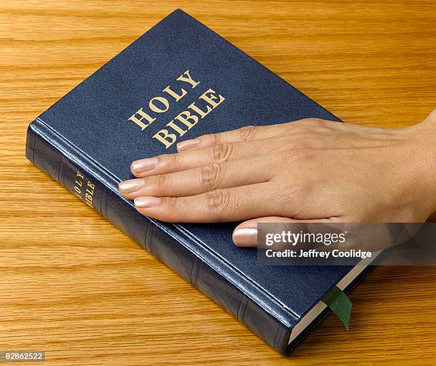 woman's hand on bible - versprechen stock-fotos und bilder