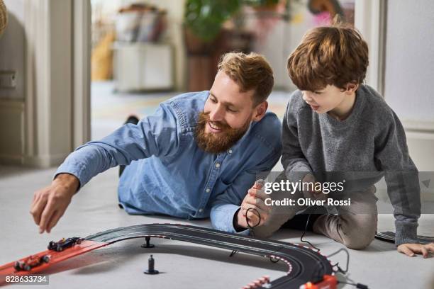 father and son playing with toy racetrack - denim shirt stock pictures, royalty-free photos & images