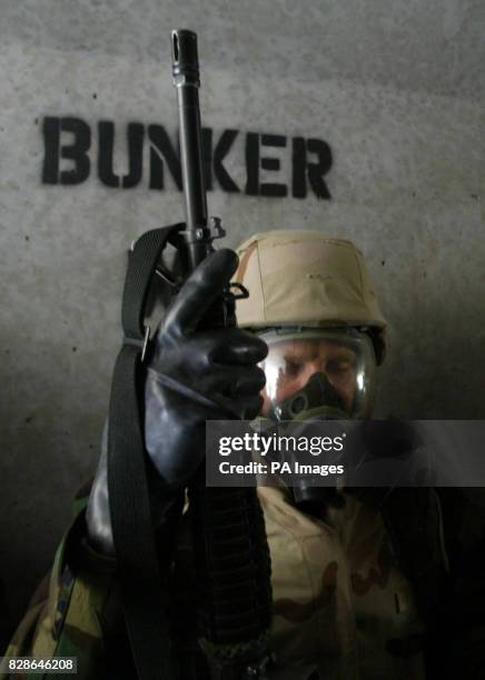 Marine closes his eyes as he waits in a full nuclear biological and chemical protection suit in a bunker at a desert base in Kuwait after a warning...