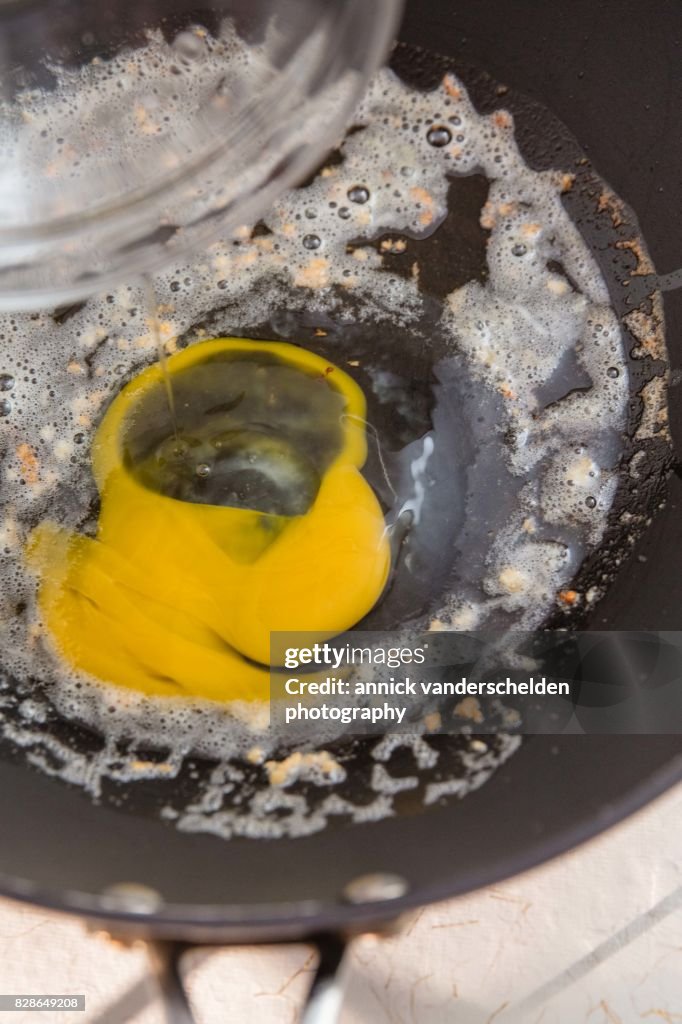 Adding egg to olive oil. butter and minced garlic in a wok.