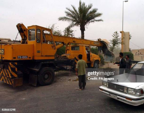 Local people drive a crane through a poster of Saddam Hussein in Basra, after Desert Rats and Royal Marines launched two waves of attacks Sunday,...