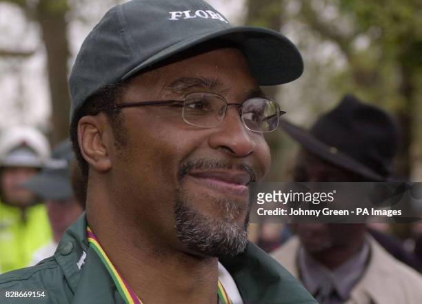 Former boxer Michael Watson celebrates after crossing the finishing line in the 2003 London Marathon on The Mall in central London, as his uncle, the...