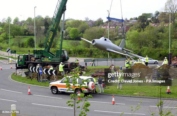 Mobile crane places a full scale replica of a jet aircraft on a traffic roundabout, south of Lutterworth, Leicestershire. The aircraft replica is a...