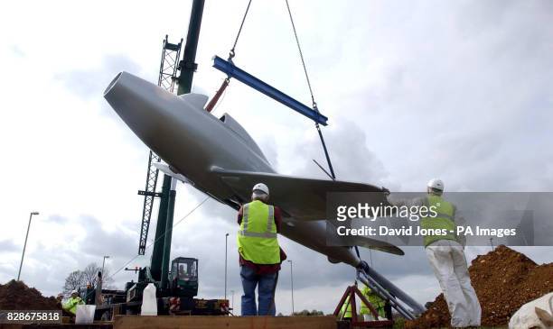 Mobile crane places a full scale replica of a jet aircraft on a traffic roundabout, south of Lutterworth, Leicestershire. The aircraft replica is a...