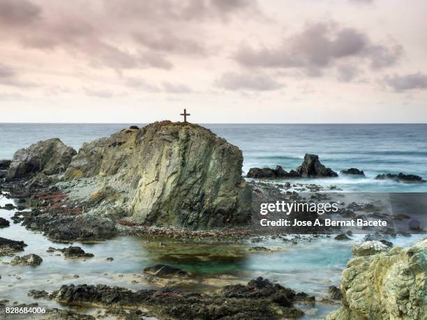 landscape of cliffs and islands in the sea, with a cross of wood in the top of an island, at the end of tabarca island in alicante, valencian community, spain. - tabarca stockfoto's en -beelden