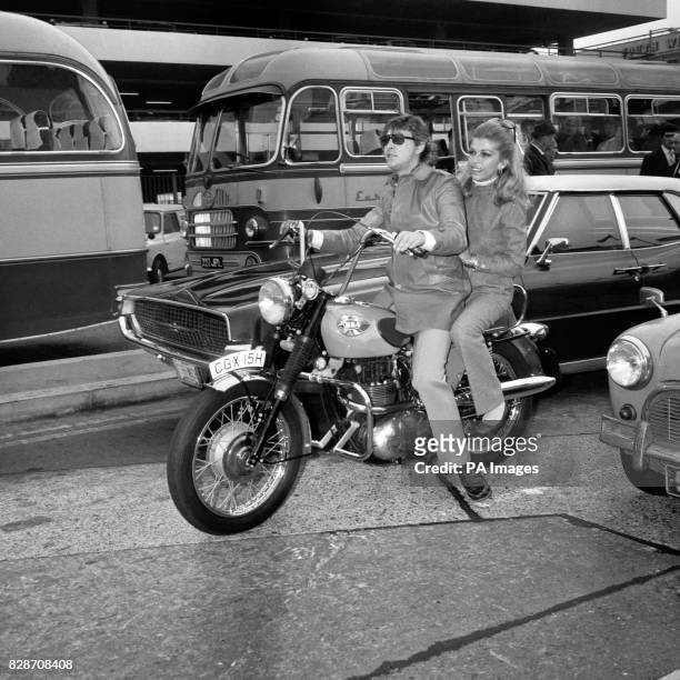 Nancy Sinatra ready to break into a song of the road as she prepares to roar along on the back of a motor bike with record producer Mickey Most in...