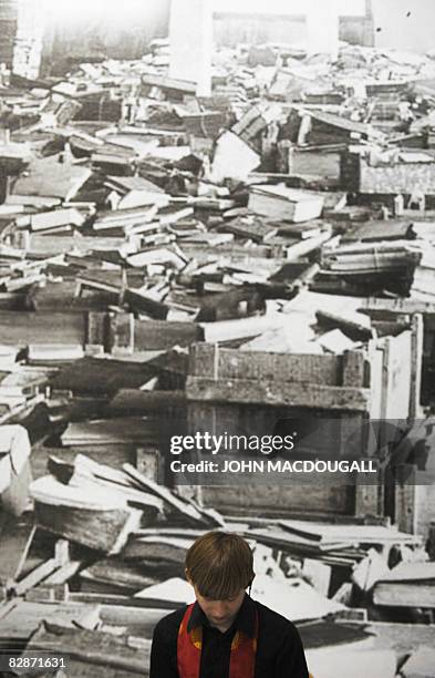 Museum attendant sits in front of a photograph featuring looted books in a storage facility near Frankfurt between 1945 and 1949, on display at the...