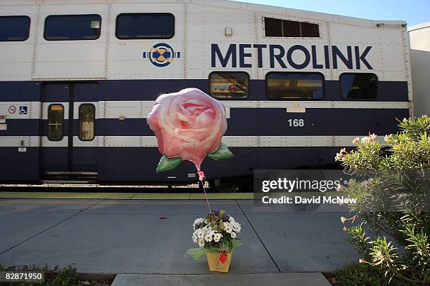 Bouquet of flowers and a balloon stands on the passenger platform as a Metrolink commuter train passes the Moorpark Metrolink train station, just...