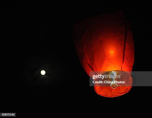 The moon shines above as residents fly the Kongming Sky Lantern to mark the Mid-Autumn Moon Festival on September 14, 2008 in Chengdu, Sichuan...