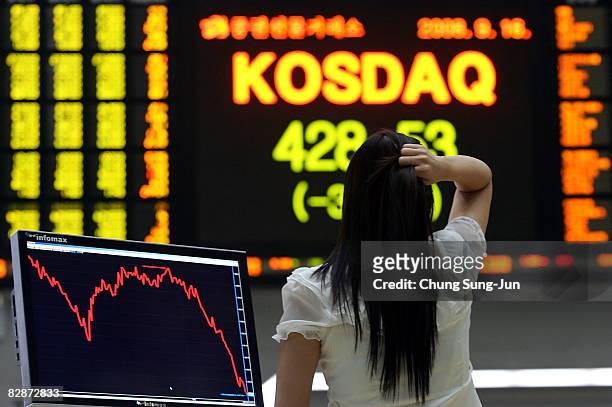 Woman looks at a board showing stock price index at a stock brokerage firm on September 16, 2008 in Seoul, South Korea. The Korean Won has plummeted...
