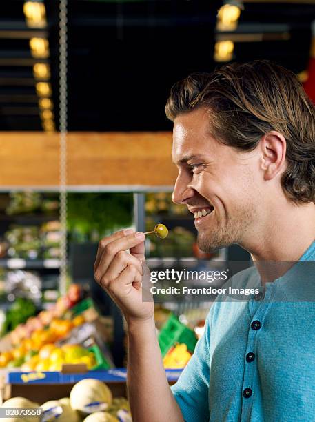 young man tasting an olive - cocktail stick stock pictures, royalty-free photos & images