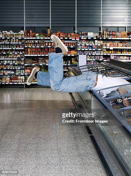 young man jumping into refrigerator.  - gier stock-fotos und bilder