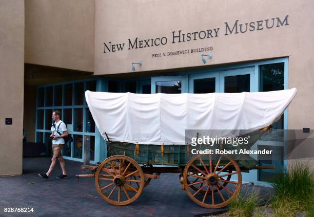 Visitor inspects a Conestoga wagon on display in front of the New Mexico History Museum in Santa Fe, New Mexico. Such wagons were used to transport...