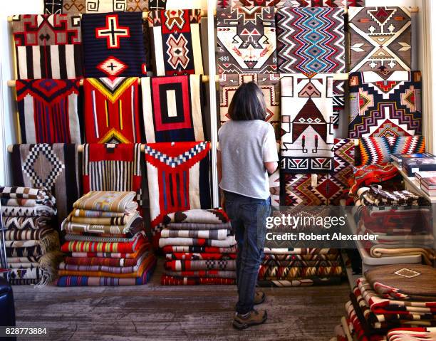 Visitor admires Native American rugs made by weavers from the Navajo Nation for sale in a shop in Santa Fe, New Mexico.