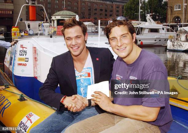 Pop star and Princes's Trust Ambassador Will Young receives a cheque from Bear Grylls for the Princes's trust, in St Katherines Dock in Central...