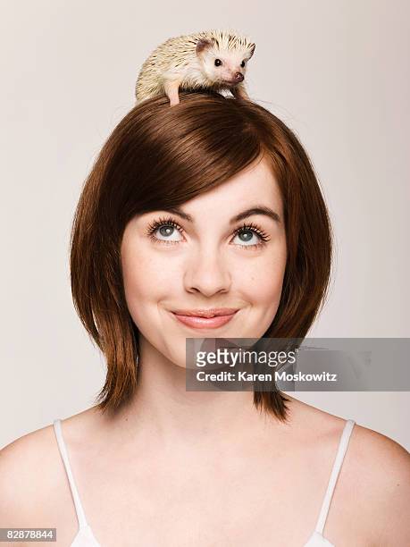 portrait of young woman with hedgehog on her head - hedgehog stock pictures, royalty-free photos & images