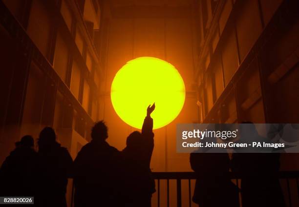 Children observe Olafur Eliasson's installation entitled 'The Weather Project' in Turbine Hall inside the Tate Modern on the Southbank in London. The...