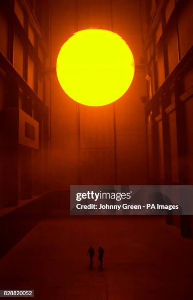 Two men walk through Turbine Hall inside the Tate Modern on the Southbank in London, surrounded by Olafur Eliasson's installation entitled 'The...