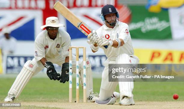 England batsman Nasser Hussain smashes the ball away during his innings watched by wicket keeper Khaled Mashud, during the afternoon session of the...