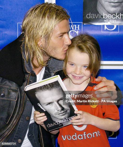 England football captain David Beckham kisses eight year-old Rebecca Gregory as she holds a copy of the soccer star's autobiography 'My Side'. The...