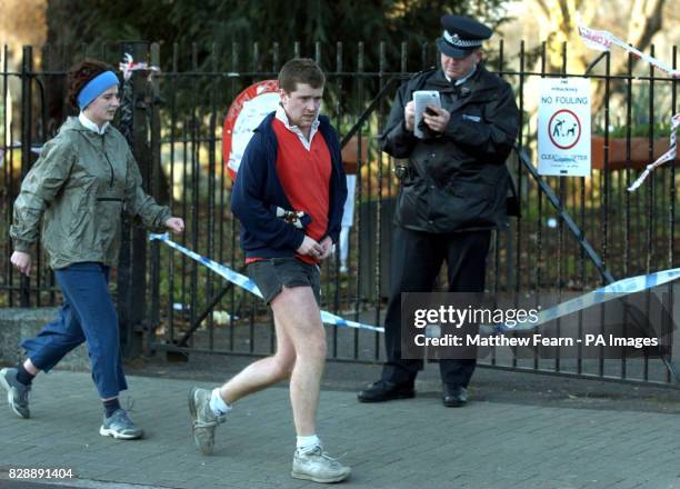 Joggers run past a police officer outside a sealed-off Clissold Park in Stoke Newington, east London, after a jogger was attacked yesterday....