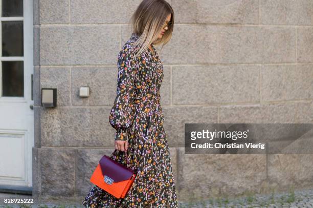 Guest wearing white boots, dress with floral print outside Holzweiler on August 09, 2017 in Copenhagen, Denmark.