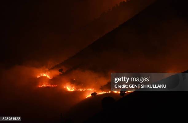 Picture taken late on August 9, 2017 shows flames and smoke rising from a forest in fire near Sarande in the Muzina mountain region, southern...