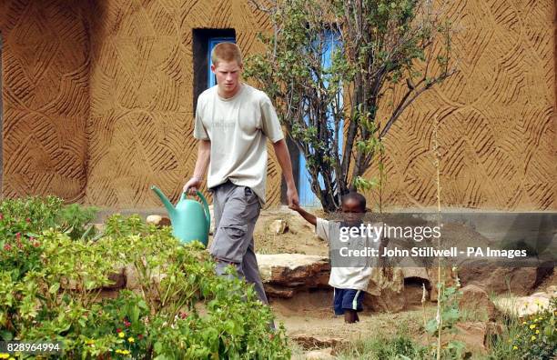 Prince Harry, the younger son of Britain's Prince Charles, leads young orphan Mutsu Potsane by the hand to plant a peach tree together at the...