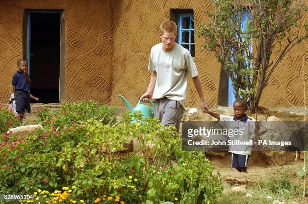Prince Harry, the younger son of Britain's Prince Charles, leads young orphan Mutsu Potsane to plant a peach tree together at the Mants'ase...