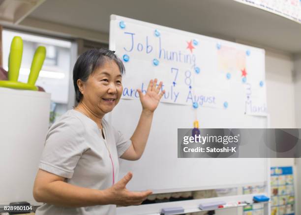 年配の女性の就職活動のプレゼンテーションを与えて - 日本人　英語 ストックフォトと画像