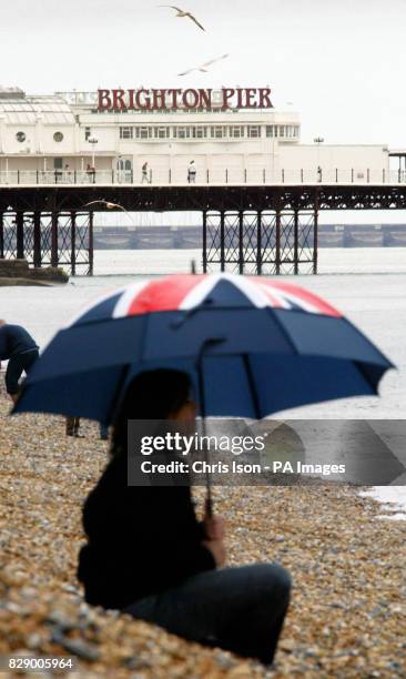 Easter daytrippers take cover on Brighton beach, Sussex, as rain showers speckled the south coast.