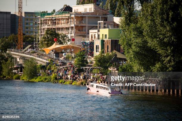 Picture taken on August 9, 2017 shows people visiting the urban cooperative project Holzmarkt 25 on the banks of the river Spree in Berlin. The...