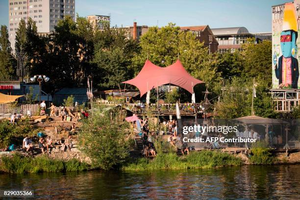 Picture taken on August 9, 2017 shows people visiting the urban cooperative project Holzmarkt 25 on the banks of the river Spree in Berlin. The...