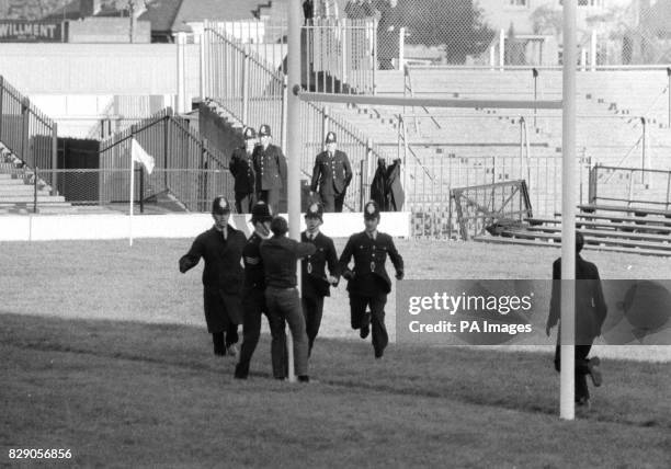 Man about to be tackled by policemen as he tries to climb a goalpost at Twickenham rugby ground, where the Springboks were meeting Oxford University...